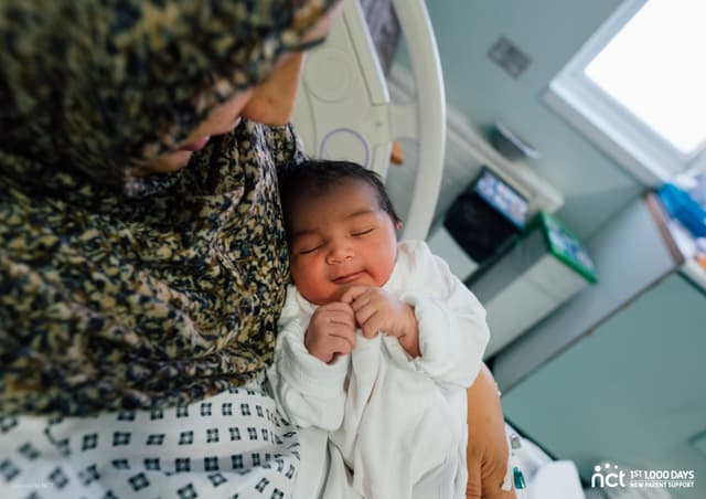 Mum holding baby in hospital bed