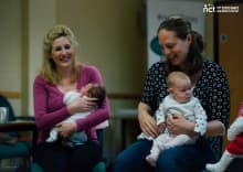 two mums smiling with their babies